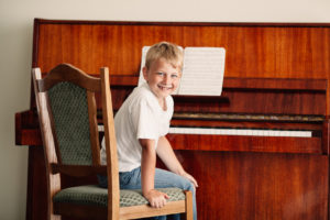 little happy boy plays piano at home
