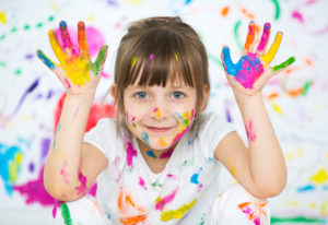 Portrait of a cute cheerful happy little girl showing her hands painted in bright color
